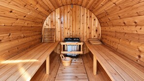 A sauna with wooden walls and benches, a bench with a towel, and a bucket with a towel. - 2 bedroom Guest Suite with Pool & Sauna access (West Vancouver)