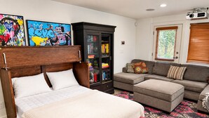 A bedroom with a bed, a sofa, a cabinet, and two wall art pieces.