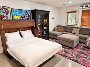 Une chambre à coucher comprenant un lit, un canapé, une armoire et deux œuvres d’art murales.