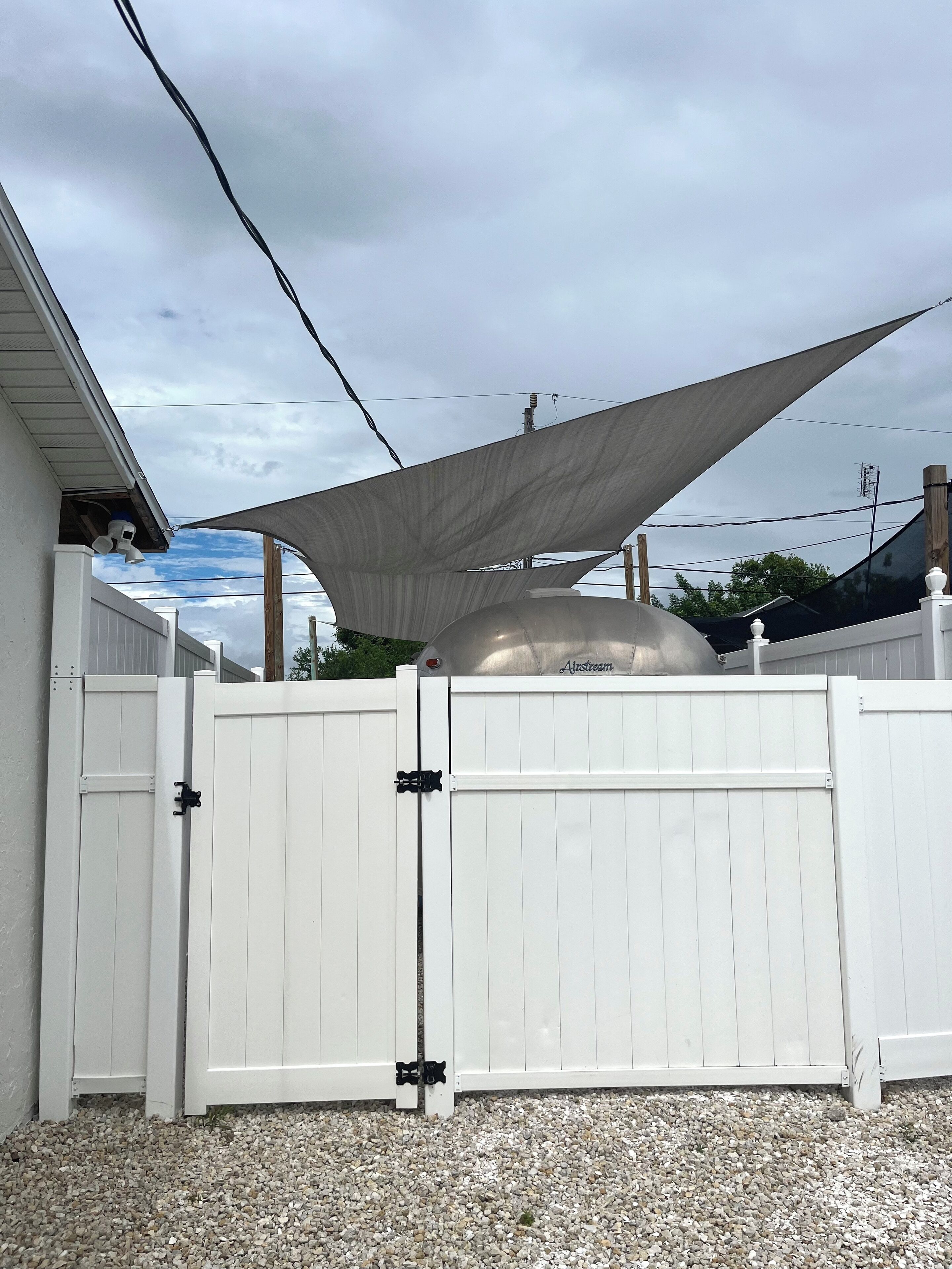 A white fence with a large umbrella-like shade structure above it.