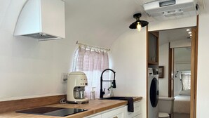 A compact kitchen with white cabinets, a wooden countertop, and a built-in washing machine. - Englewood retreat just 12 minutes from the beach (Englewood)