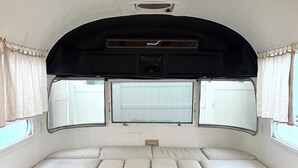 A compact RV interior with a bed, overhead storage, and windows. - Englewood retreat just 12 minutes from the beach (Englewood)