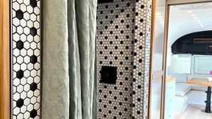 A room with a hexagonal patterned wall, a sliding door with a curtain, a white cabinet, and a wooden table with a chair. - Englewood retreat just 12 minutes from the beach (Englewood)