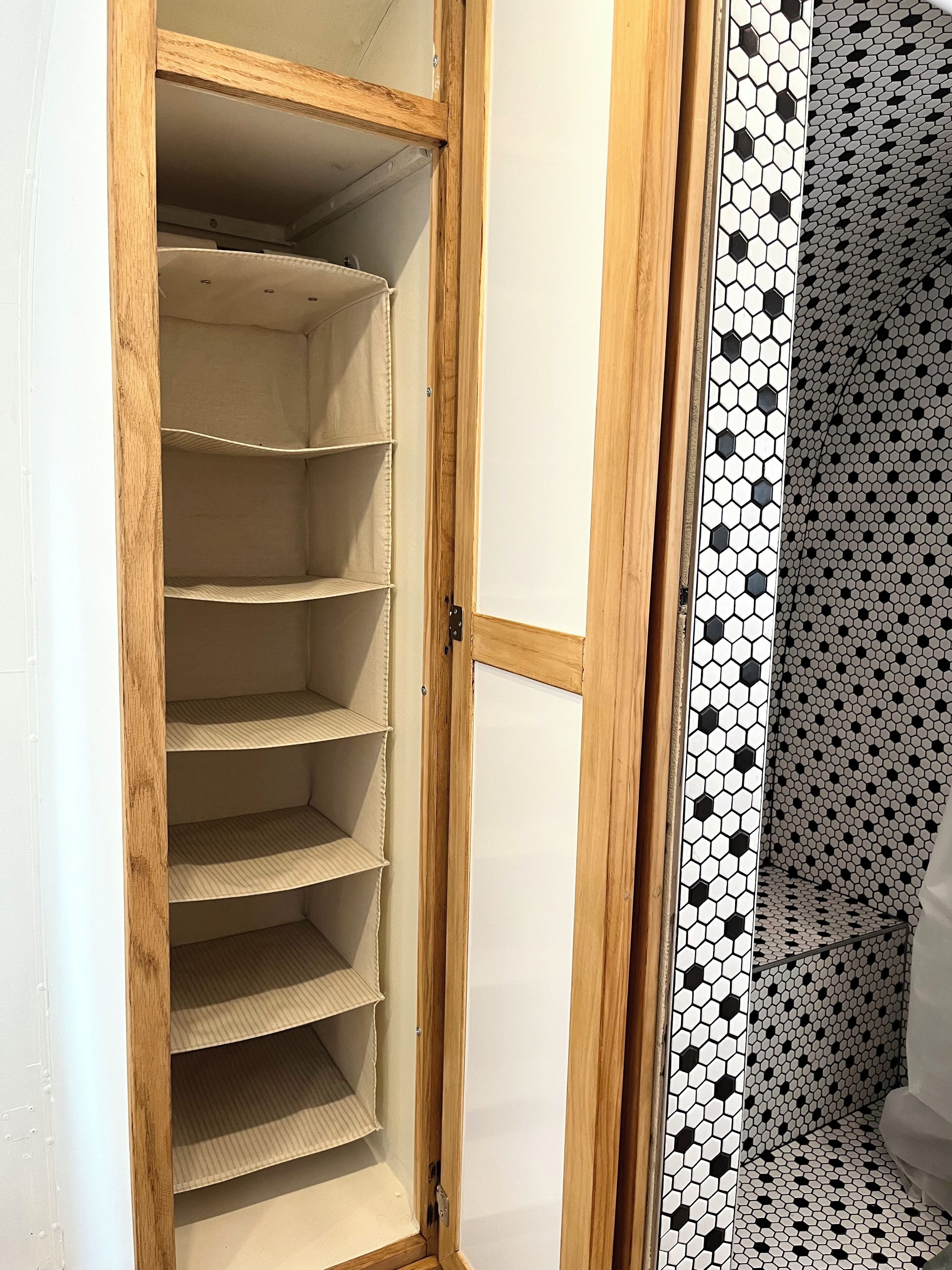 A wooden closet with multiple shelves and a tiled wall with a geometric pattern.