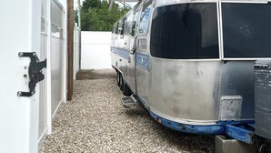 A vintage bus parked under a canopy, with gravel ground and a white fence in the background. - Englewood retreat just 12 minutes from the beach (Englewood)