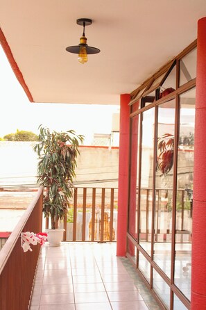 A balcony with a potted plant, a hanging light fixture, and a view of the outside. - Lidia Anturios Suites (Oaxaca)