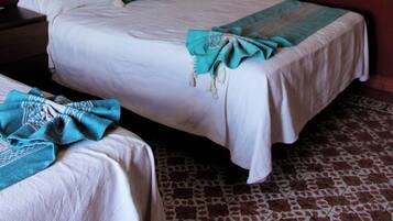 A hotel room with two beds, a dark headboard, a plain wall, and a patterned floor.