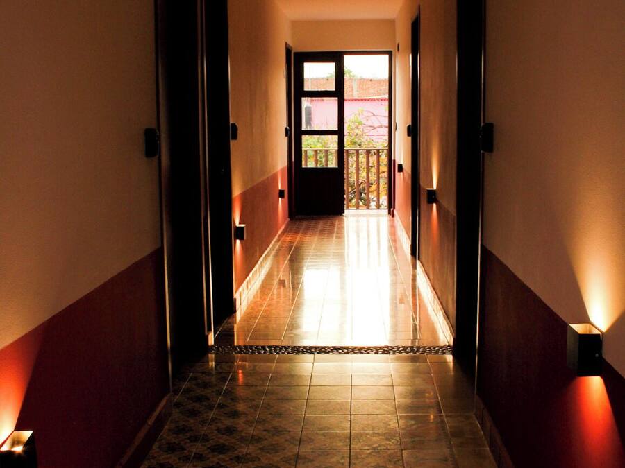 Un pasillo con baldosas de diseño, puertas a ambos lados y luces fijadas a la pared.