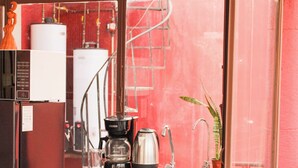 A compact kitchen with a wooden cabinet, a coffee maker, a kettle, and a sink. - Lidia Anturios Suites (Oaxaca)