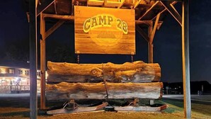 Une structure en bois sur laquelle est apposée une pancarte indiquant « CAMP 28 », de nuit.