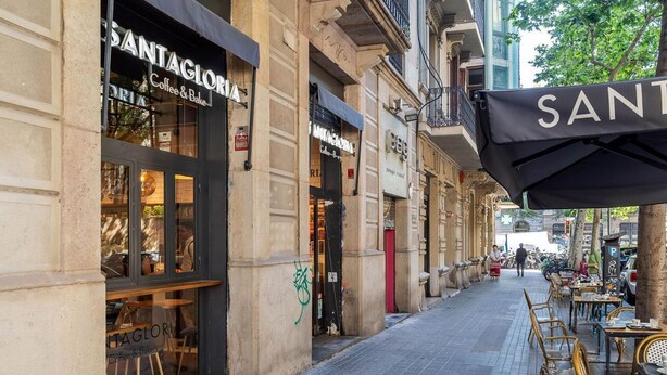 A street with cafes, including 'Santagloria Coffee & Bake,' and outdoor seating. - Beautiful apartment near Plaza Catalunya (Barcelona)