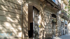 A building facade with a metal gate, a sign reading 'KANAY,' and a number '15' above the entrance. - Beautiful apartment near Plaza Catalunya (Barcelona)