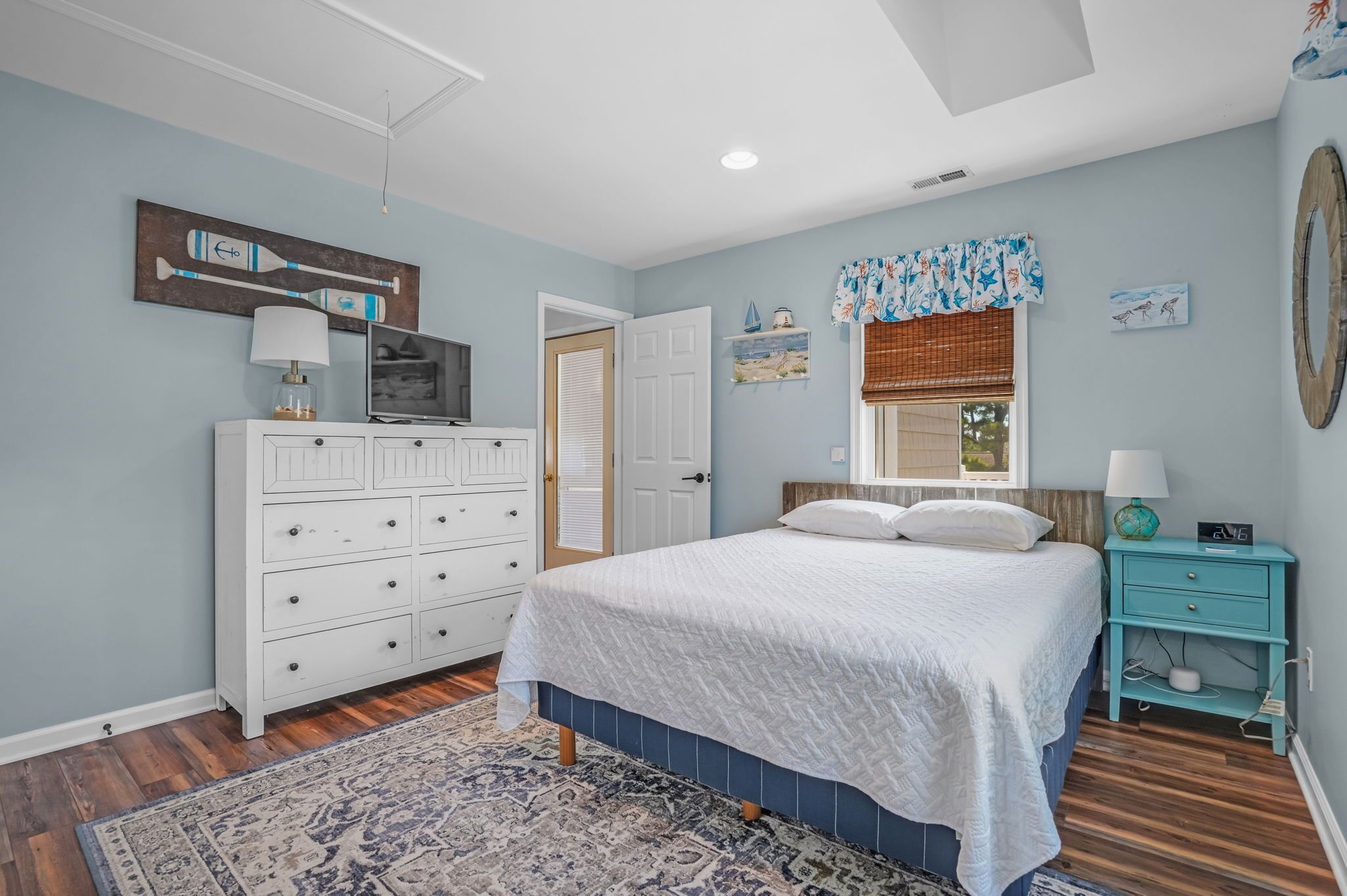 A bedroom with a bed, dresser, and a window with blinds.