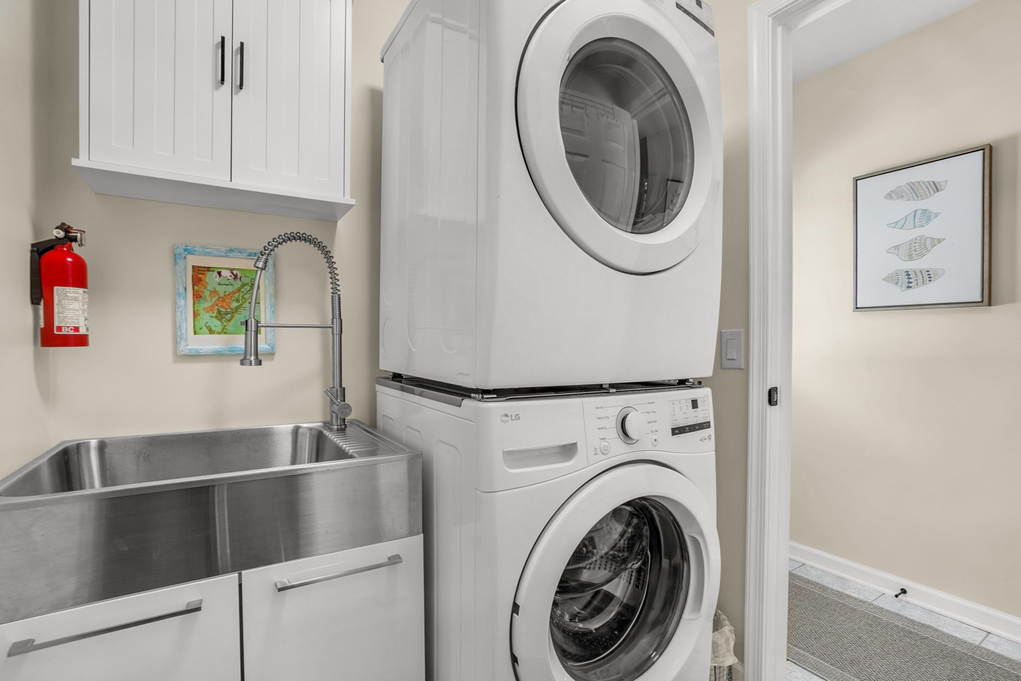 A laundry area with a washing machine, a sink, and cabinets.
