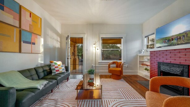 A modern living room with a green sofa, orange armchair, and a fireplace. - Close to UofA / 1 BR 1 BA / Unique / Patio & Porch (Tucson)