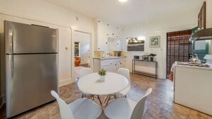 A modern kitchen with a stainless steel refrigerator, white cabinetry, and a dining area with a round table and white chairs. - Close to UofA / 1 BR 1 BA / Unique / Patio & Porch (Tucson)