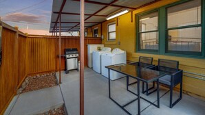 A covered outdoor area with a table and chairs, a washing machine, and a grill. - Close to UofA / 1 BR 1 BA / Unique / Patio & Porch (Tucson)