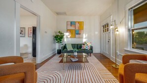 A modern living room with a green sofa, orange armchairs, a coffee table, and a patterned rug. - Close to UofA / 1 BR 1 BA / Unique / Patio & Porch (Tucson)