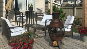 Une terrasse en bois avec des meubles d’extérieur, une pergola et un grand bac à fleurs.