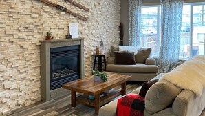 Un salon avec un mur en briques, une cheminée, un canapé et une table basse.