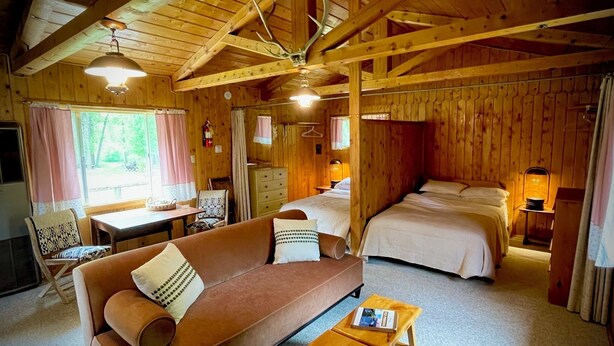 Ein gemütliches Blockhausschlafzimmer mit Sofa, einem kleinen Holztisch, einem Bett und einem Essbereich.