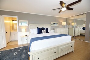 A bedroom with a bed, bedside tables, a ceiling fan, a mirror, and a rug.
