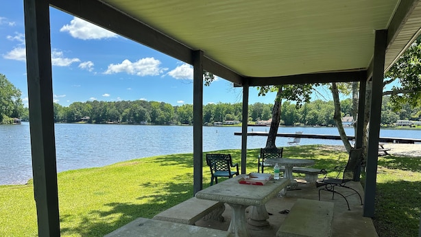 A covered outdoor area with a table and chairs, overlooking a lake with ducks swimming. - Lake Cabin, 10 minutes from Callaway Gardens  (West Point)