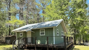 A small, single-story cabin with a wooden deck and a porch, surrounded by trees. - Lake Cabin, 10 minutes from Callaway Gardens  (West Point)