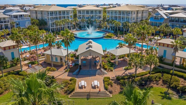 A resort with a central pool, multiple guest buildings, and palm trees.