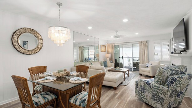 A spacious living room with a dining area, a large mirror, and a ceiling fan.