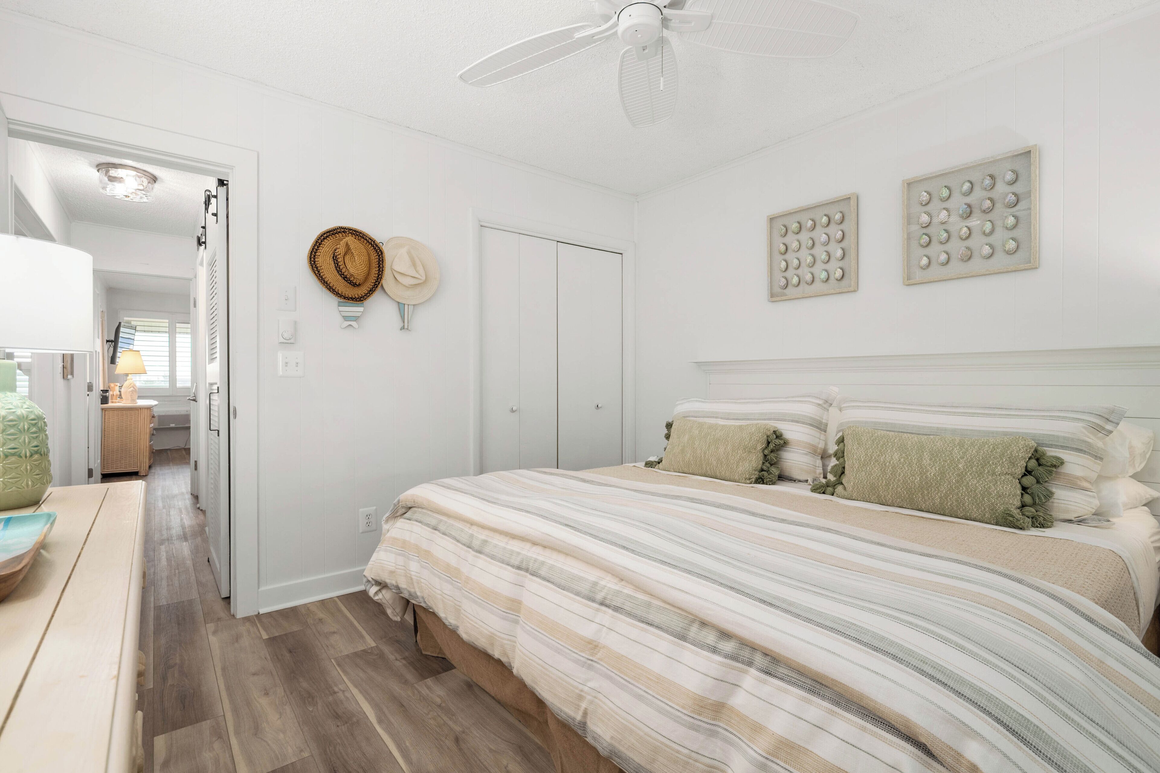 Un dormitorio con una cama grande, un ventilador de techo, un armario y una mesita de noche con una lámpara.