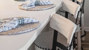 A dining area with a white table set with plates, glasses, and a decorative vase.