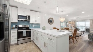 A modern kitchen with white cabinets, stainless steel appliances, and a large island.