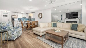 A modern living room with a sofa, coffee table, and a dining area with chairs and a table.