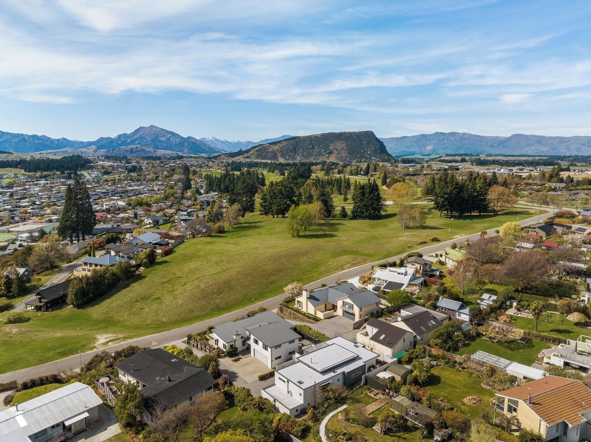 A residential area with houses, green spaces, and a mountain in the background.