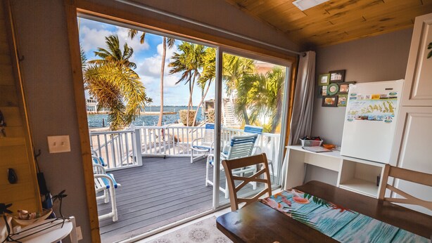 A room with a view of a deck, a dining table, and a refrigerator. - Pelicans View - Venture Out Lot 318 (Cudjoe Key)