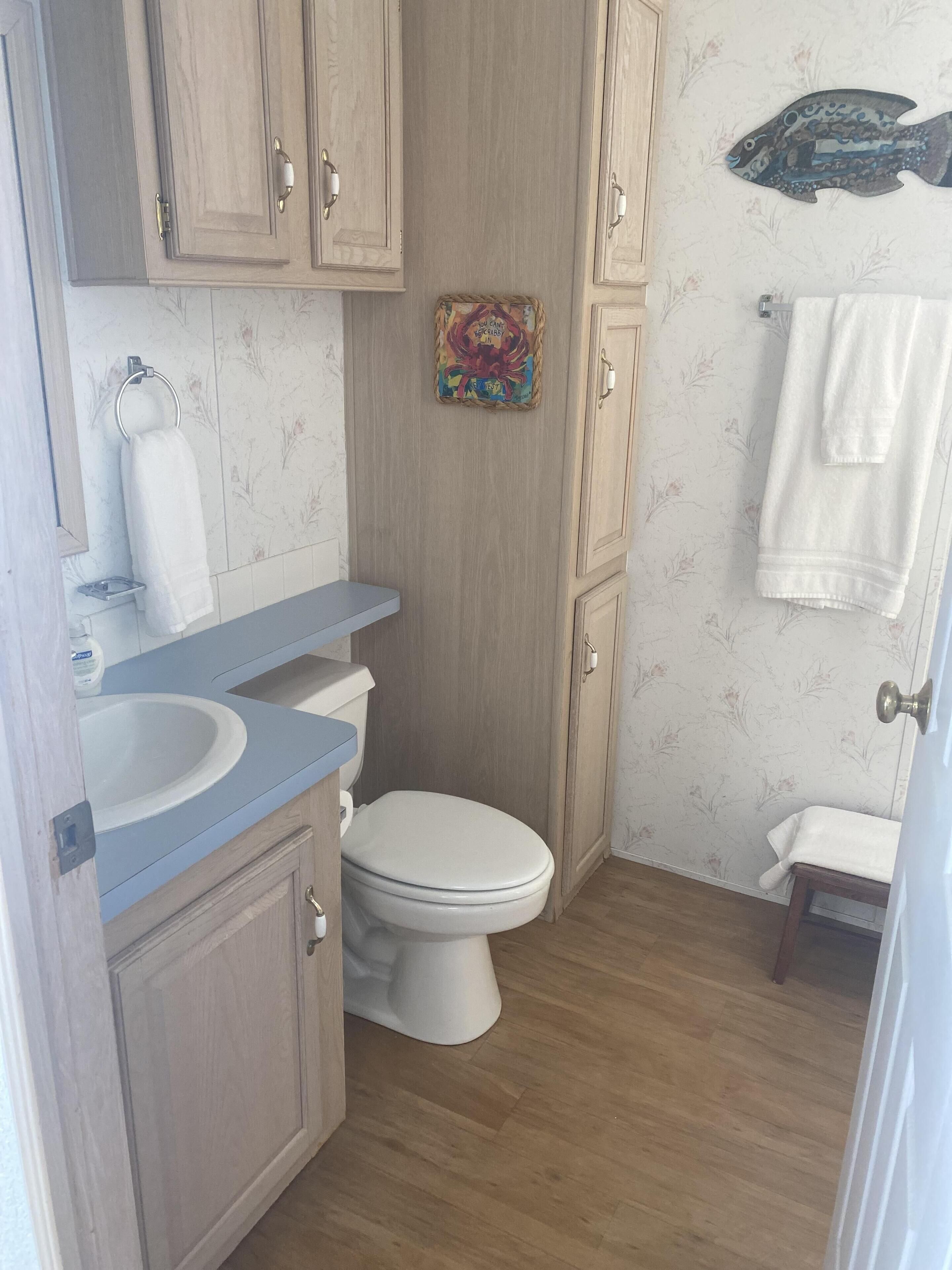 A bathroom with a wooden vanity, a toilet, a sink, and a shower area.