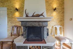 Una chimenea con cuernos en la parte superior, flanqueada por dos sillones, en una habitación con paredes de ladrillo.