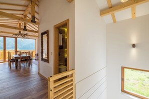 Eine Holztreppe führt zu einem Raum mit einem Fenster, einem Essbereich mit Tisch und Stühlen sowie einem Spiegel an der Wand.