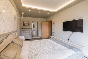 Un dormitorio con cama, cómoda, tocador y televisor.