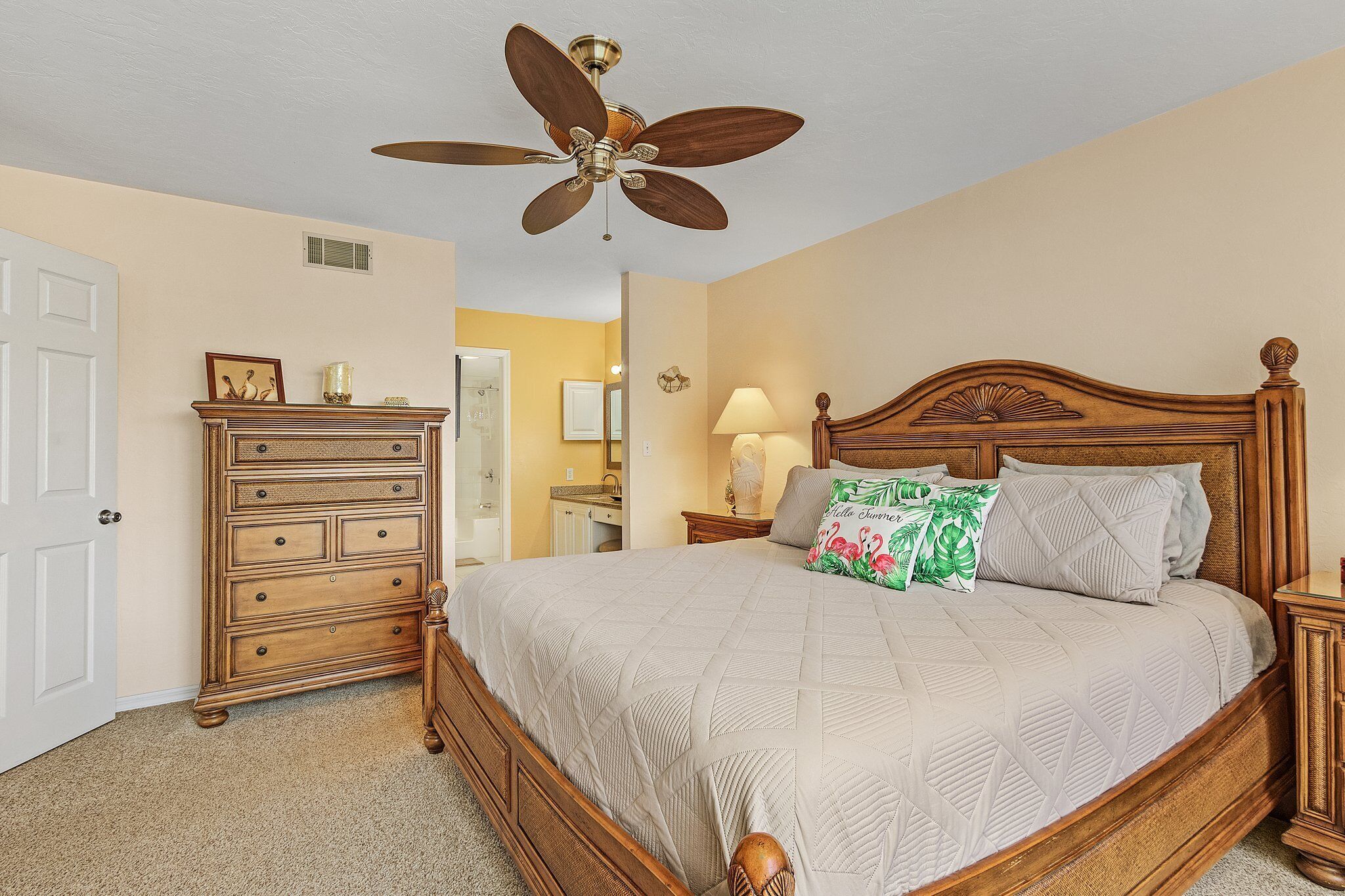 Un dormitorio con una cama de madera, ventilador de techo, cómoda y mesita de noche.