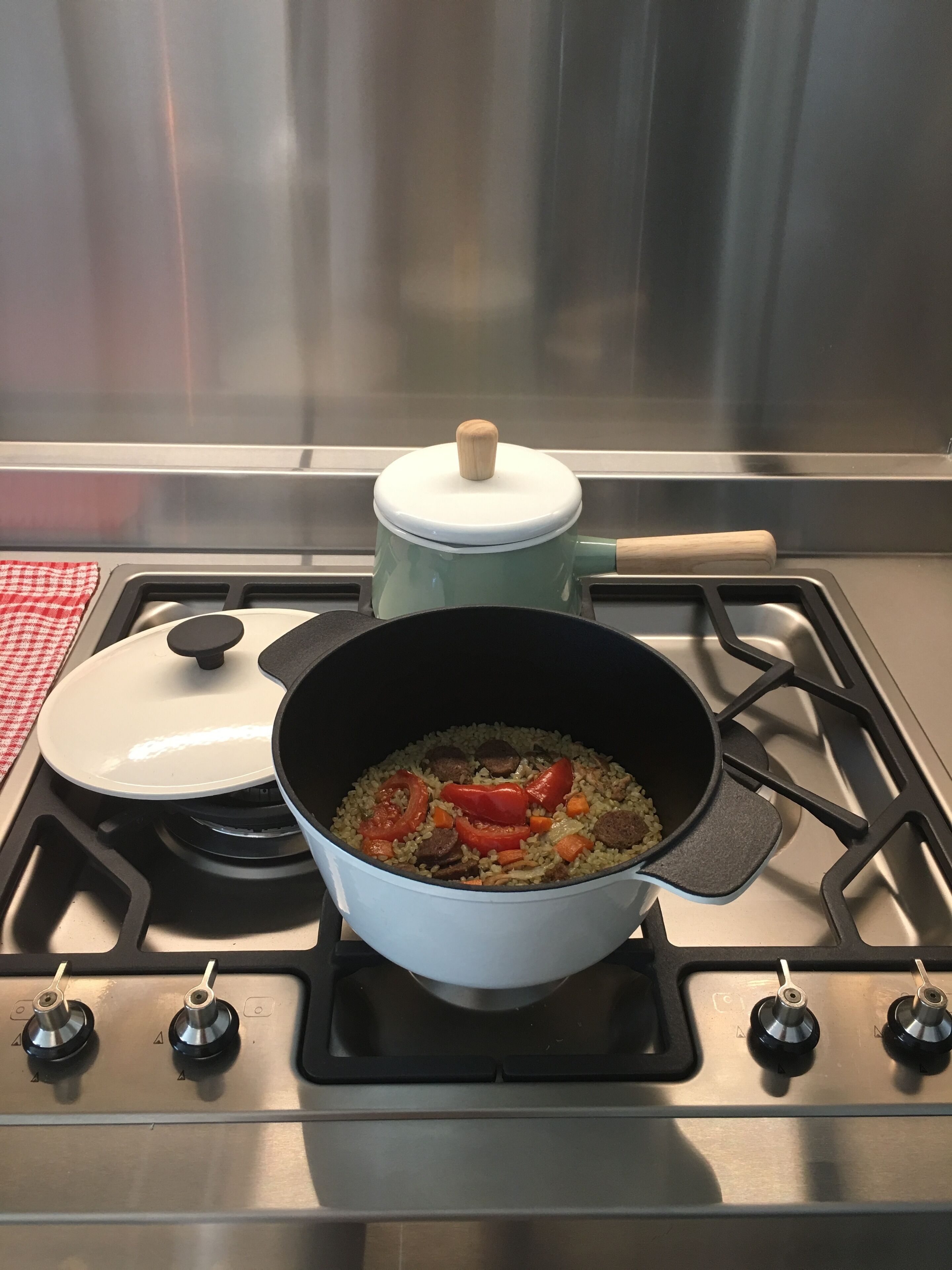 Un fornello da cucina con una pentola di cibo, una padella e un coperchio.
