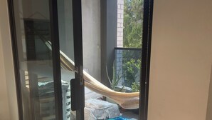 A room with a sliding glass door leading to an outdoor area with a hammock and a patterned rug.