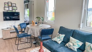 Ein modernes Wohnzimmer mit einem blauen Sofa, einem Couchtisch mit einer Vase und einem Essbereich mit Tisch und Stühlen.