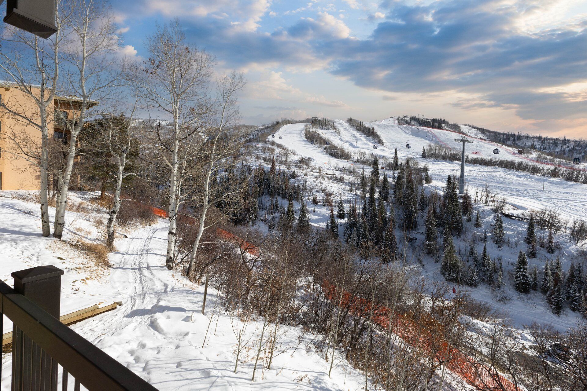 A snowy landscape with a ski slope, trees, and a building in the background.