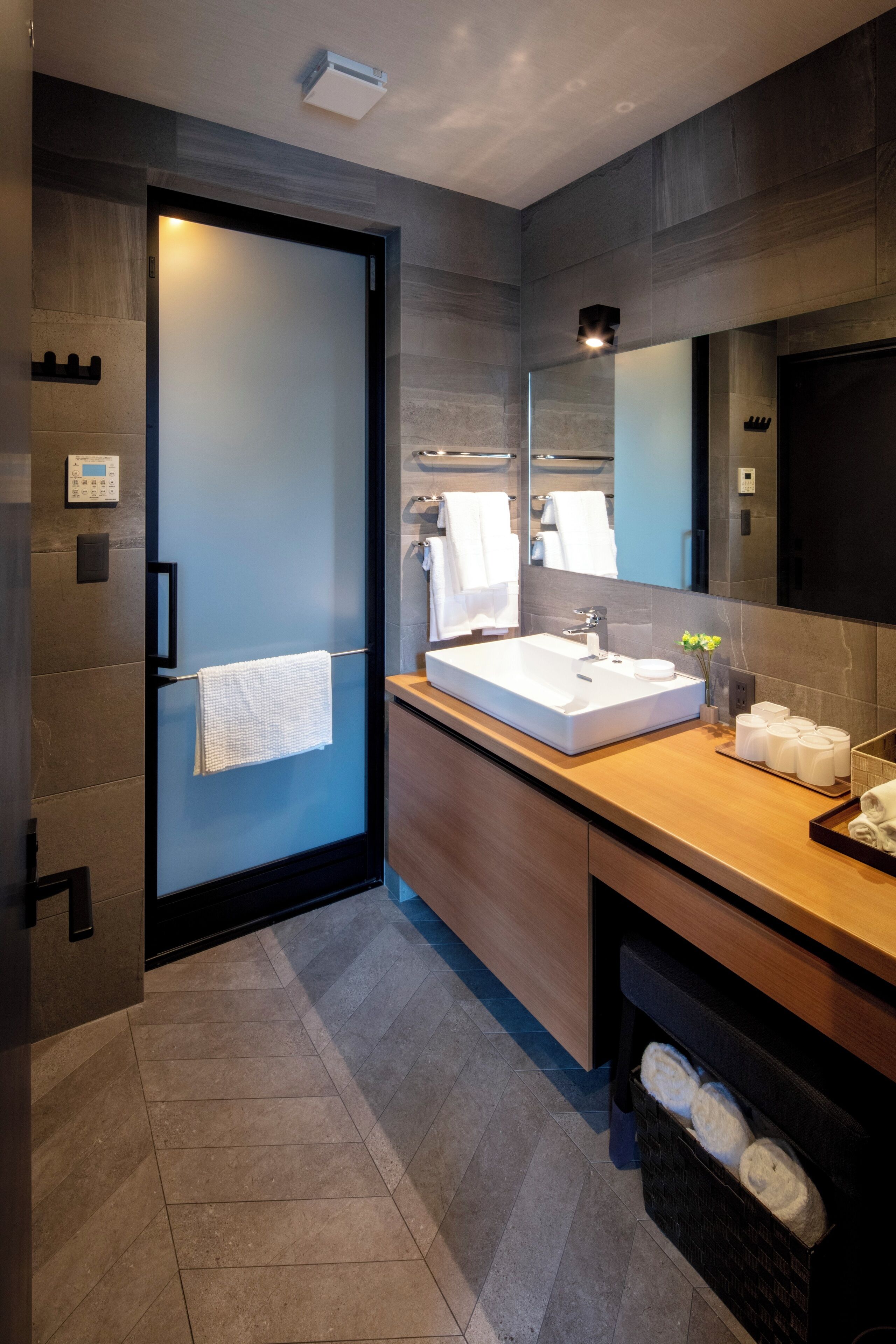 Un baño moderno con mampara de vidrio, un lavamanos espacioso y un espejo.