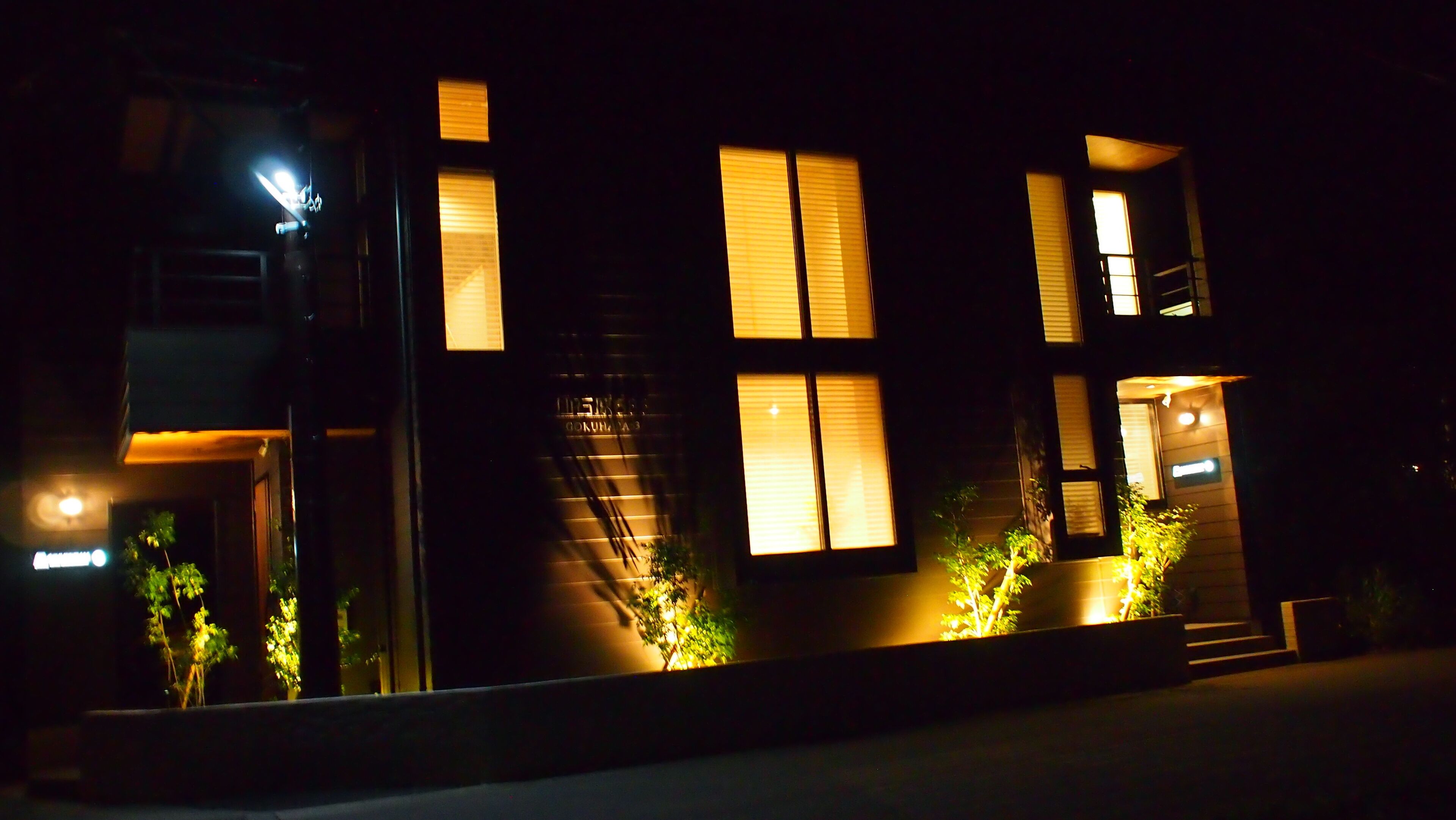A modern building with illuminated windows and a visible staircase leading to an upper floor.