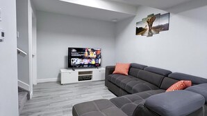 A modern living room with a sectional sofa, a flat-screen TV, and a minimalist design. - Guest Suite in SouthWest Edmonton (Edmonton)