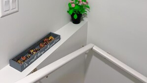 A bathroom with a framed motivational quote, a small potted plant, a mirror, and a tray with chocolates. - Guest Suite in SouthWest Edmonton (Edmonton)