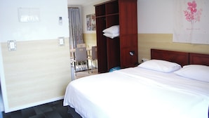 Una habitación de hotel con una cama, un armario de madera, un escritorio y una silla.